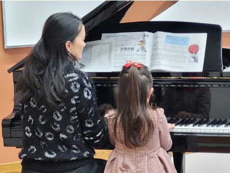 Jufang teaching a young student at the grand piano